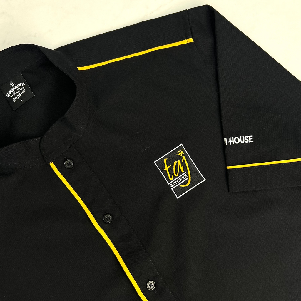 Black restaurant uniform shirt with yellow piping and custom embroidered logo